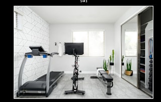 A home gym with a treadmill, rowing machine, and bench press.