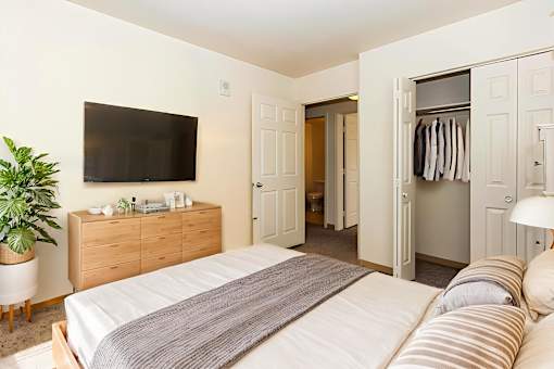 A bedroom with a bed, a TV, and a cabinet.