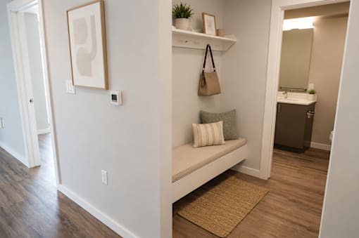 A hallway with a bench and a painting on the wall.