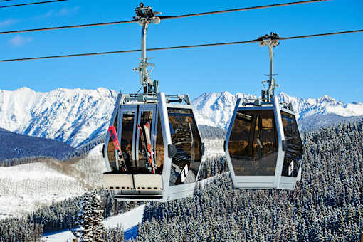 Two cable cars are suspended above a snowy mountain landscape.
