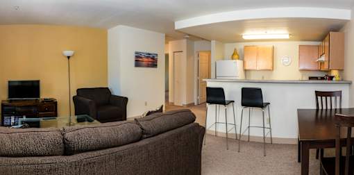 A living room with a couch, chairs, and a television.