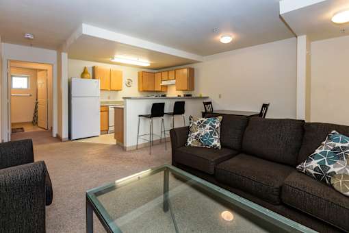 A living room with a couch, chairs, and a glass table.