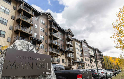 A large apartment complex named "Main Vail" is shown with cars parked in front.