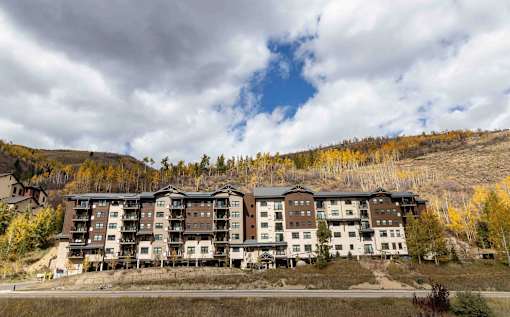 A large building with many windows is situated in front of a hill.