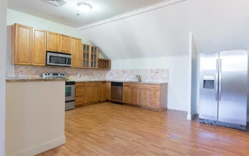 an empty kitchen with wooden cabinets and a stainless steel refrigerator