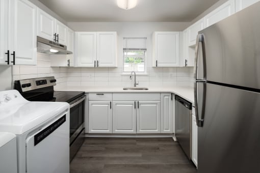 a white kitchen with stainless steel appliances and white cabinets