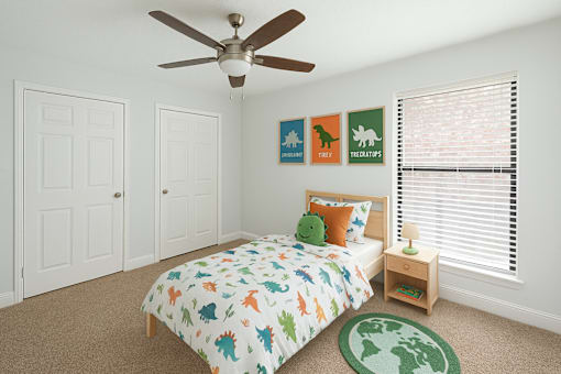 A bedroom with a bed, a ceiling fan, and a carpet with a map of the world on it.