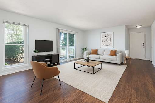 A living room with a white couch, orange chair, and a painting on the wall.