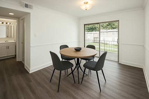 A dining room with a round table and four chairs.
