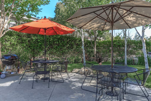 a patio with two tables and two umbrellas