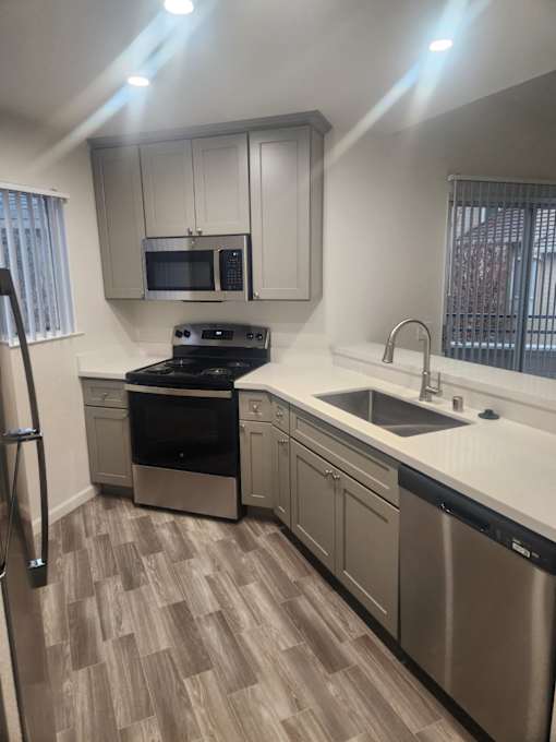 A kitchen with a stove, oven, sink, and microwave.