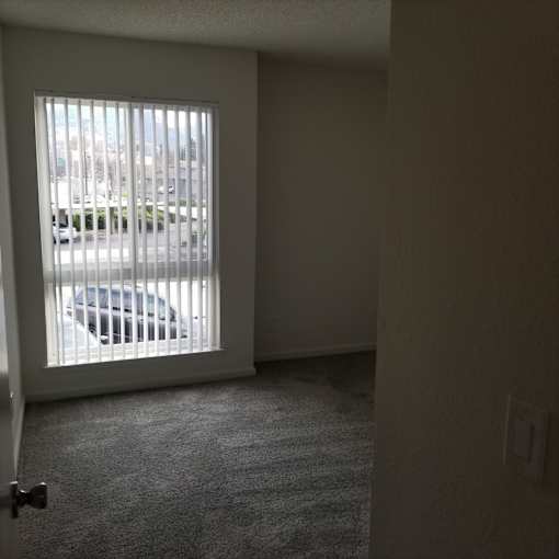 A car is parked outside a window with blinds.
