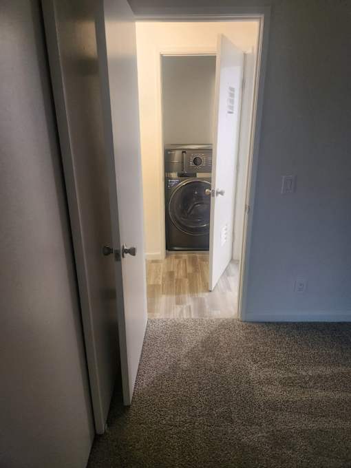 A white door is open to a room with a washer and dryer.