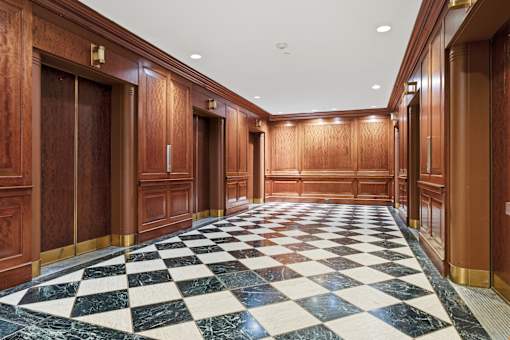 A hallway with a checkered floor and wooden doors.
