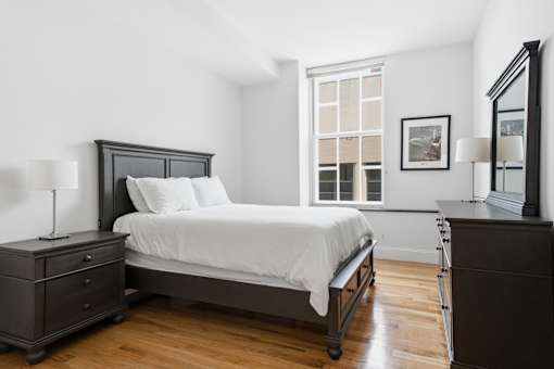 A bedroom with a bed, nightstand, and dresser.