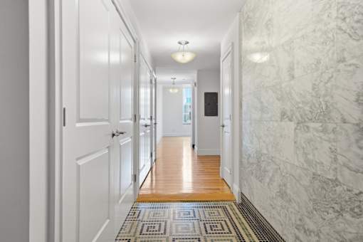 A hallway with marble walls and a tiled floor.