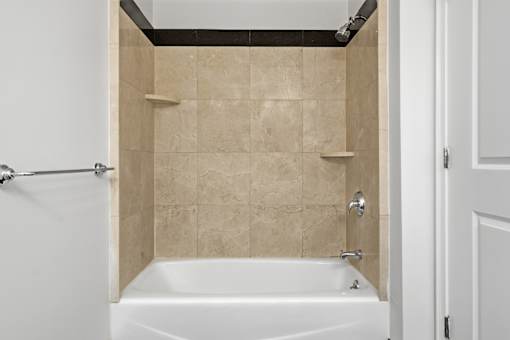 A white bathtub with a shower head and a shower curtain rod.