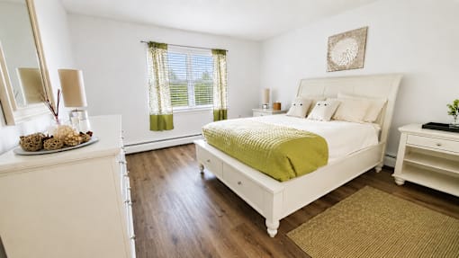 A bedroom with a white bed and a green blanket.