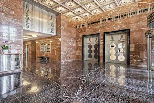 A hallway with a marble floor and a brown wall.