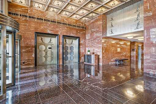 A marble hallway with a bench and a chandelier.