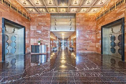 A hallway with marble floors and walls, with a date stamp of 1878-1935.