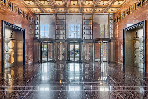 A hallway with a black marble floor and a ceiling with recessed lighting.