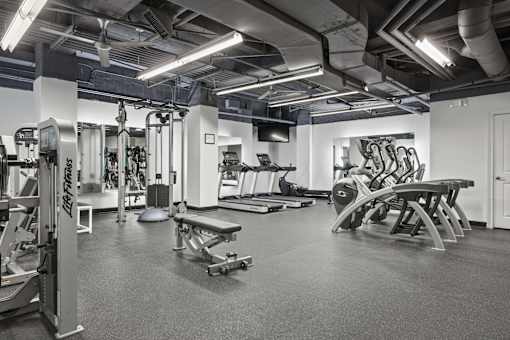 A black and white photo of a gym with various exercise equipment.