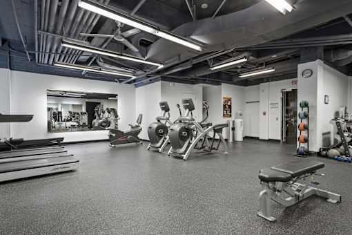 A gym with a variety of exercise equipment including treadmills, rowing machines, and weight machines.