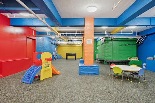 A play area with a slide, a table and chairs.