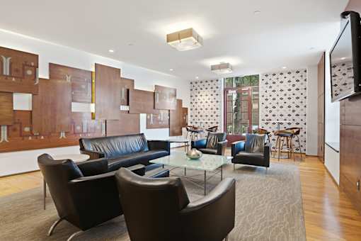 A modern living room with a black leather couch and a glass coffee table.