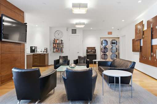 A living room with a television, leather chairs, and a coffee table.