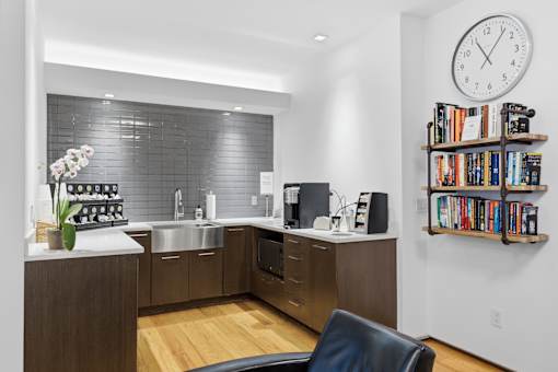A modern kitchen with a black chair and a clock on the wall.