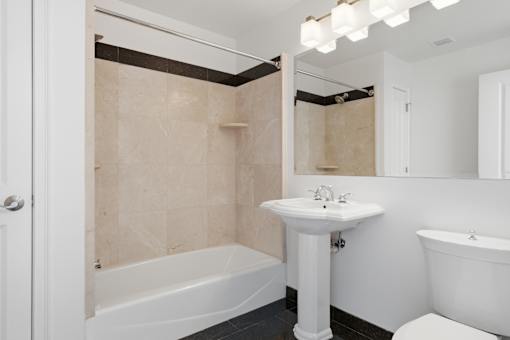 A white bathroom with a tub, sink, and mirror.