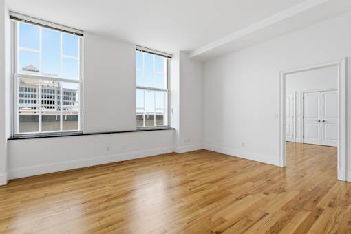 A room with wooden floors and a large window overlooking a cityscape.