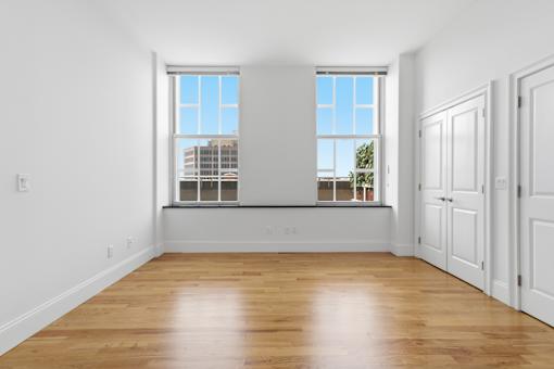 A room with wooden floors and two windows.