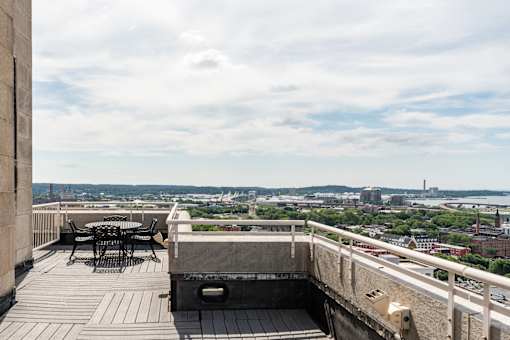 A balcony with a table and chairs overlooking a cityscape.