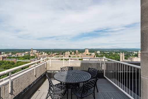A balcony with a table and chairs overlooking a cityscape.