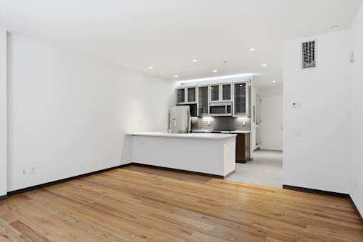 A kitchen with a white counter and wooden floors.