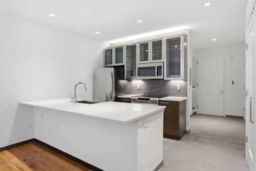 A modern kitchen with white countertops and stainless steel appliances.