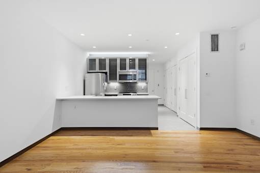A kitchen with wooden floors and white walls.