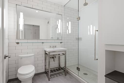 A white bathroom with a toilet, sink, and mirror.