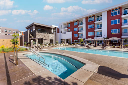 A swimming pool with Amara apartment building in the backgroundwith a red and white facade.