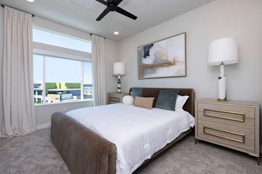 A bedroom with a large bed, large windows and a ceiling fan