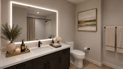 A bathroom with a white toilet, a sink with a mirror above it, and a plant on the counter.