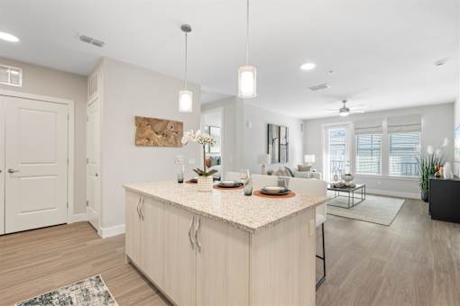 a kitchen with a large island open to a living room with large windows at Mira at Palmer Ranch, Sarasota