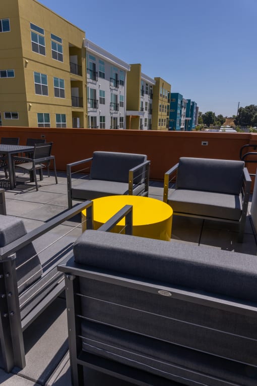 a patio with chairs and a yellow table on a roof