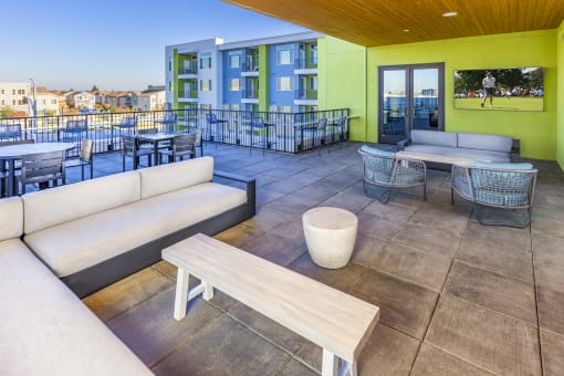 Outdoor balcony resident lounge with  large screen tv , seating and table and chairs at Zeta Luxury Apartments in Sacramento, CA