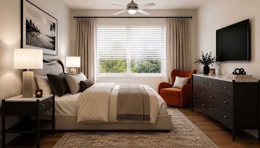 A well-lit bedroom with a large bed, a chair, and a television.