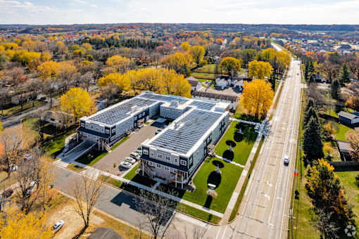 A large building with a grey roof is surrounded by trees with yellow leaves.