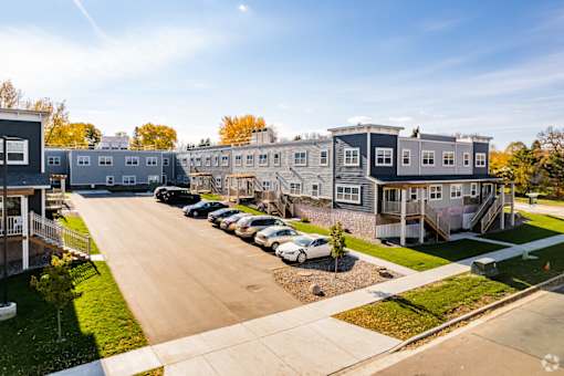 A row of houses with cars parked in front.